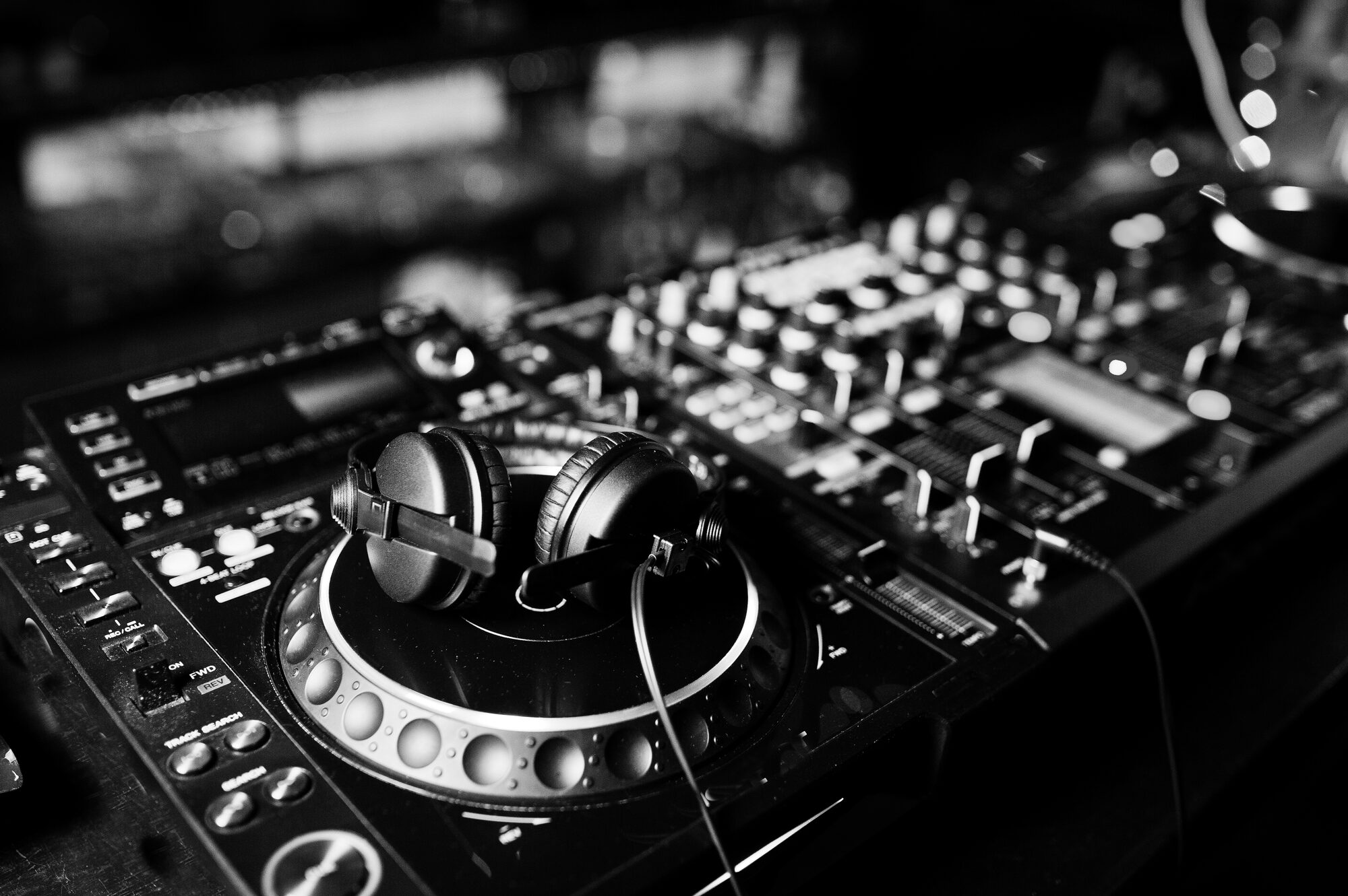 Headphones resting on a DJ deck, close-up black and white